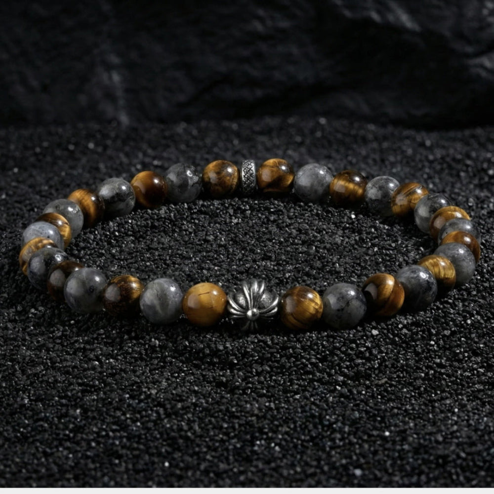 Natural tiger eye hawk eye stone bracelet resting on dark wood beside a leather watch and linen cloth, soft daylight, masculine grounded everyday atmosphere, handmade crystal jewelry for men.