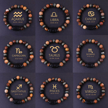 Natural zodiac stone bracelet showing three-color alternating beads — warm chatoyant tiger eye, blue-green hawk eye and dark agate — with engraved black obsidian zodiac symbol charm on elastic cord.