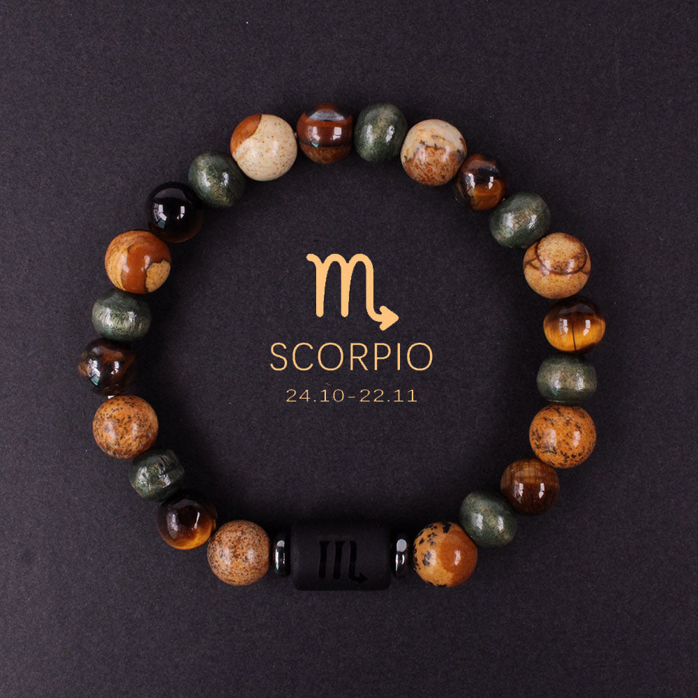 Macro detail of natural zodiac stone bracelet engraved obsidian zodiac symbol centerpiece alongside chatoyant tiger eye and silky hawk eye natural stones, polished finish, soft daylight.