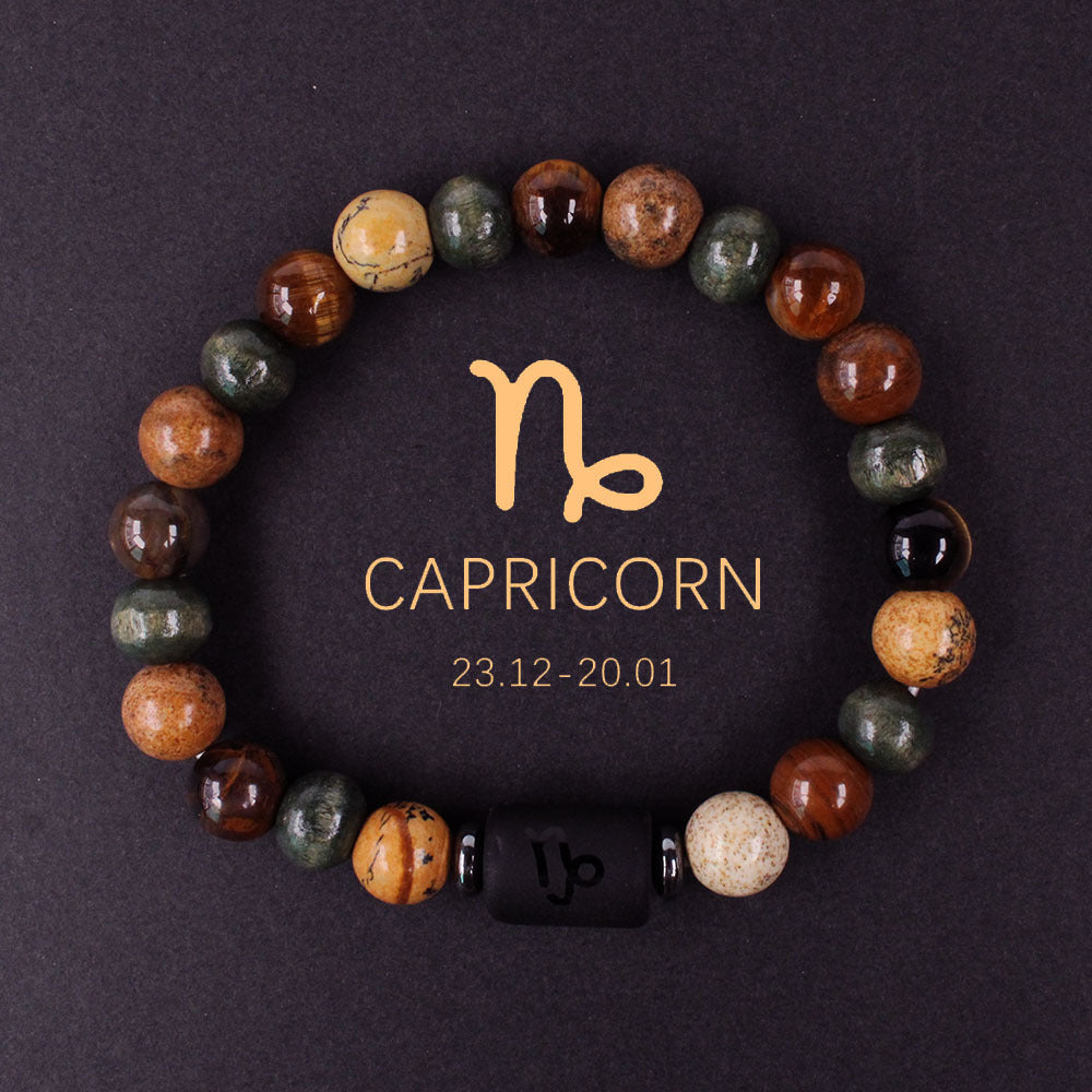 Close-up of natural zodiac stone bracelet showing engraved black obsidian zodiac symbol centerpiece, polished tiger eye hawk eye agate beads, hand-knotted elastic structure with silver accents.