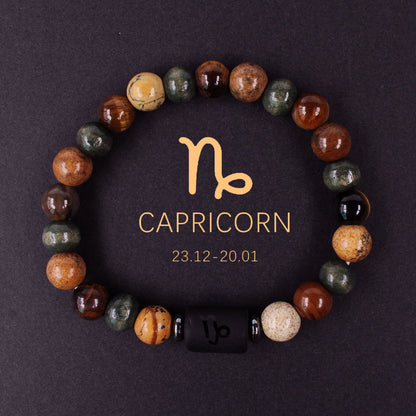 Close-up of natural zodiac stone bracelet showing engraved black obsidian zodiac symbol centerpiece, polished tiger eye hawk eye agate beads, hand-knotted elastic structure with silver accents.
