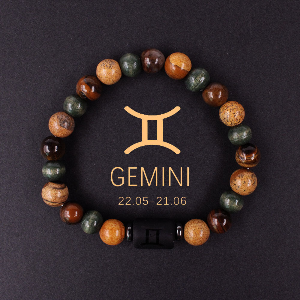 Close-up of natural zodiac stone bracelet showing engraved black obsidian zodiac symbol centerpiece, polished tiger eye hawk eye agate beads, hand-knotted elastic structure with silver accents.