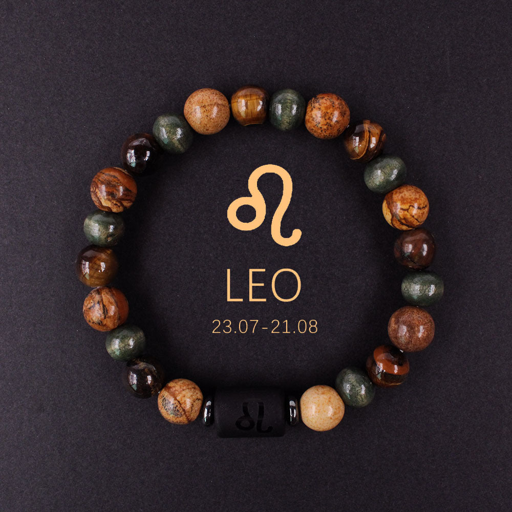 Close-up of natural zodiac stone bracelet showing engraved black obsidian zodiac symbol centerpiece, polished tiger eye hawk eye agate beads, hand-knotted elastic structure with silver accents.