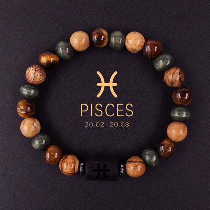 Natural zodiac stone bracelet resting on dark wood beside a leather watch and linen cloth, soft daylight, masculine grounded zodiac atmosphere, handmade crystal jewelry.