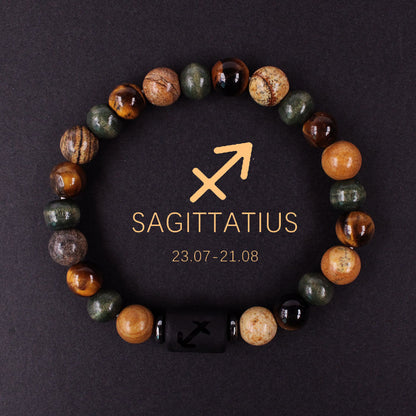 Natural zodiac stone bracelet resting on dark wood beside a leather watch and linen cloth, soft daylight, masculine grounded zodiac atmosphere, handmade crystal jewelry.