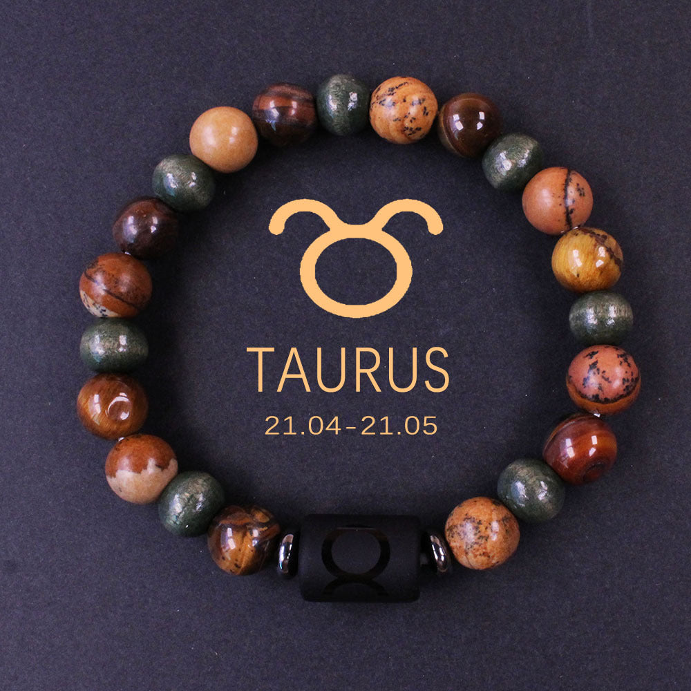 Natural zodiac stone bracelet showing three-color alternating beads — warm chatoyant tiger eye, blue-green hawk eye and dark agate — with engraved black obsidian zodiac symbol charm on elastic cord.
