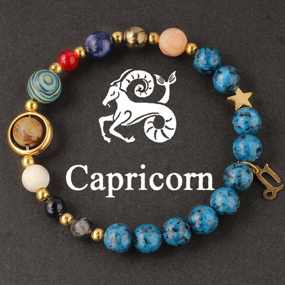 Close-up of Natural zodiac stone bracelet highlighting polished speckled blue beads, red jasper and cream accents on golden elastic strand.