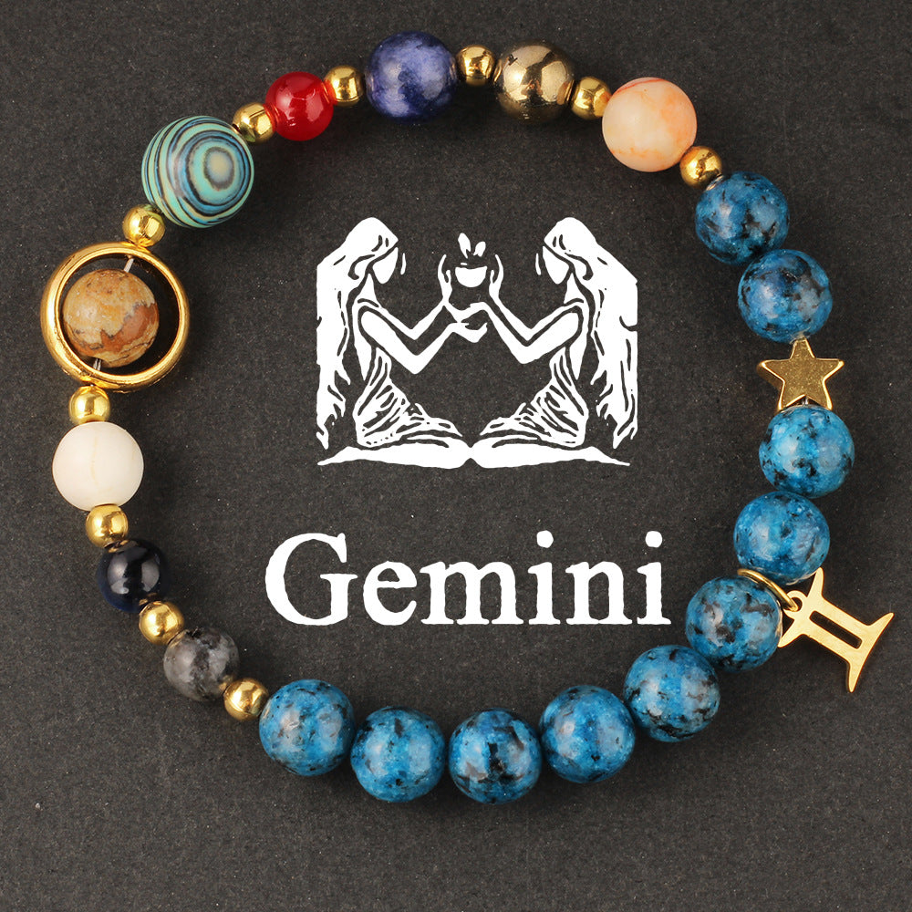 Close-up of Natural zodiac stone bracelet highlighting polished speckled blue beads, red jasper and cream accents on golden elastic strand.