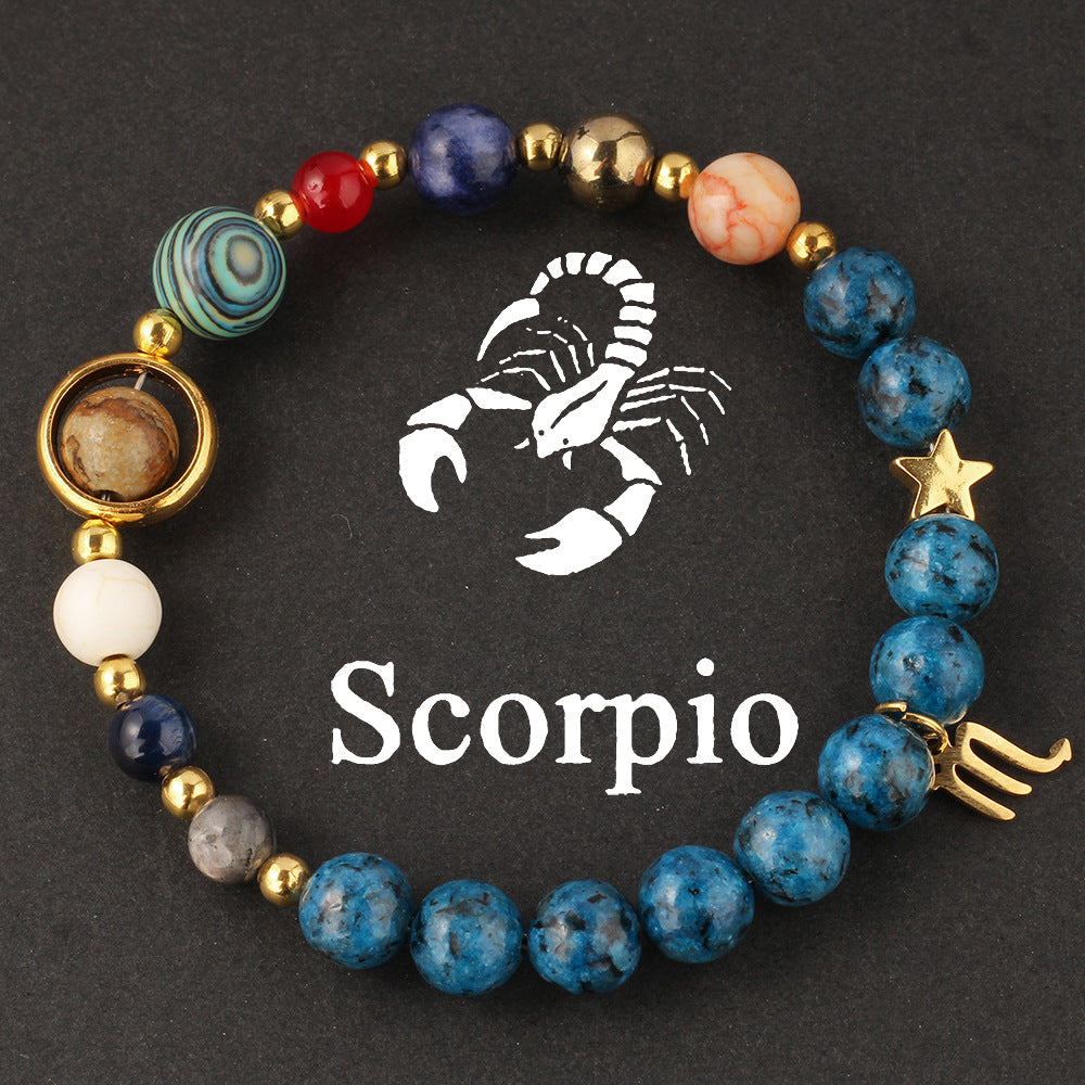 Macro detail of Natural zodiac stone bracelet Aquarius water-bearer charm in warm gold tone against speckled blue stone bead.