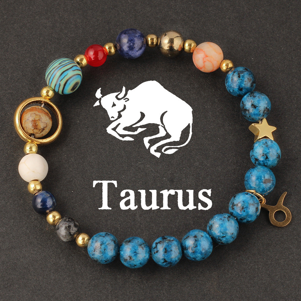 Macro detail of Natural zodiac stone bracelet Aquarius water-bearer charm in warm gold tone against speckled blue stone bead.