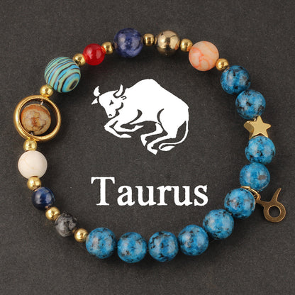 Macro detail of Natural zodiac stone bracelet Aquarius water-bearer charm in warm gold tone against speckled blue stone bead.