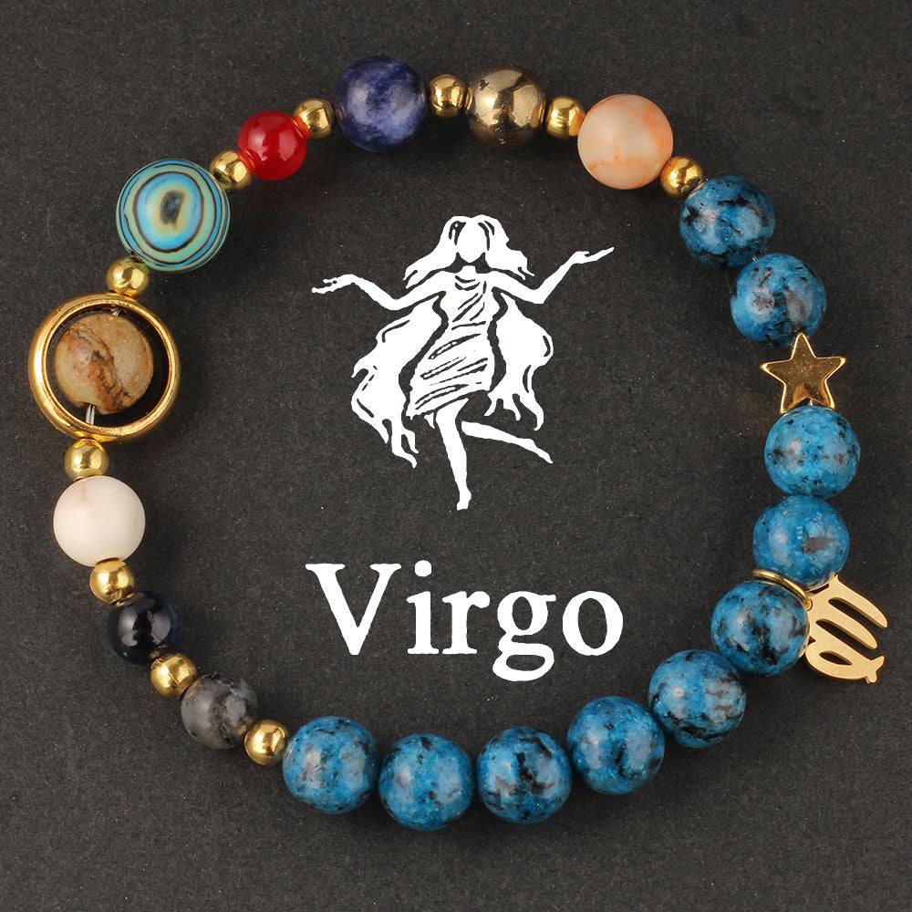 Macro detail of Natural zodiac stone bracelet Aquarius water-bearer charm in warm gold tone against speckled blue stone bead.