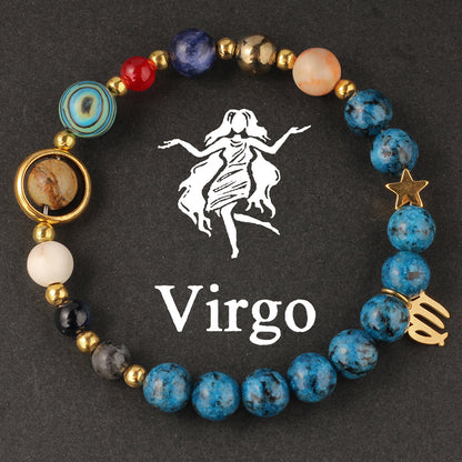 Macro detail of Natural zodiac stone bracelet Aquarius water-bearer charm in warm gold tone against speckled blue stone bead.