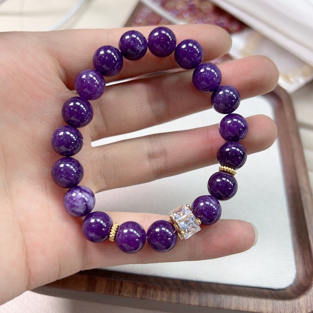 Macro detail of natural amethyst bracelet bead surface showing translucent violet depth and silky white veining, 8mm polished round finish, soft daylight.