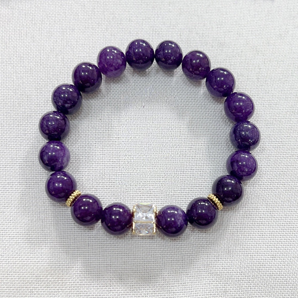 Close-up of natural amethyst bracelet beads showing 8mm polished round surface with cloud-like veining inclusions, deep violet tone with natural pattern uniqueness per bead.