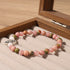 Close-up of Natural Pink Crystal Lotus Bracelet, focusing on the rose-toned stone beads, the red-green speckled accent beads and the silver lotus charm detail 