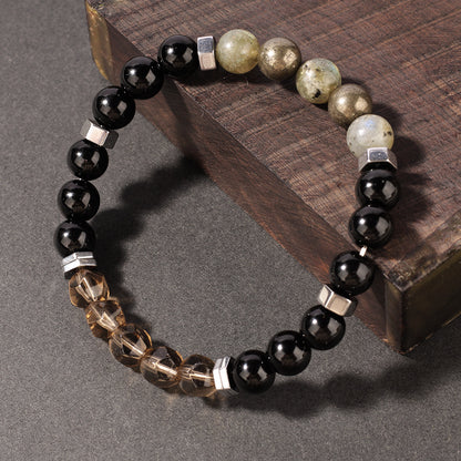 Close-up of natural obsidian labradorite bracelet detail of a single iridescent labradorite bead catching light next to a deep mirror-black obsidian bead