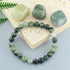  Natural Green Jade Cat Eye Bracelet on a soft travertine slab, hand-strung with smooth round nephrite jade beads showing silky cat&