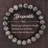 Natural Yooperlite Glow Stone Bracelet on a deep wood plate, hand-strung with smoothly polished speckled syenite beads in greys, charcoal and warm cream flecks