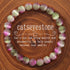Macro detail of natural cat eye stone bracelet bead surface showing translucent pink-green natural stone with luminous horizontal cat&