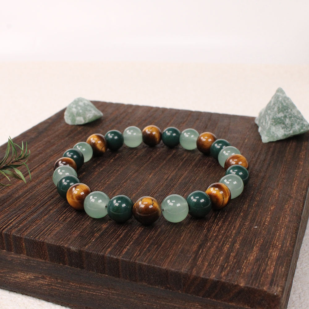 Natural tiger eye crystal stone bracelet with polished round beads alternating in warm golden-brown tiger eye, deep forest green stone and pale apple green crystal, hand-knotted on elastic cord, earthy crystal jewelry for women and men.