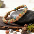 Close-up of Multi-Color Gemstone Woven Bracelet showing hand-knotted golden cord weaving between red, pink, amber, green, turquoise and ivory natural stone beads in macramé-style pattern.`