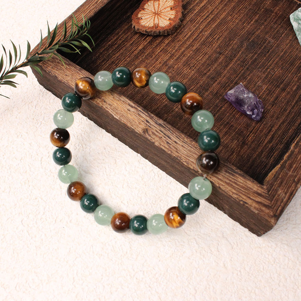 Natural tiger eye crystal stone bracelet with polished round beads alternating in warm golden-brown tiger eye, deep forest green stone and pale apple green crystal, hand-knotted on elastic cord, earthy crystal jewelry for women and men.