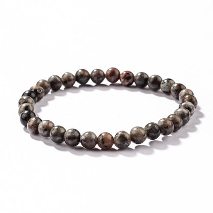 Close-up of Natural Yooperlite Glow Stone Bracelet, focusing on a single speckled syenite bead showing soft greys, charcoal clouds and warm cream flecks